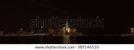 A view of the Lower Manhattan skyline at night as seen from the Hoboken waterfront. The Verrazano-Narrows Bridge and Goldman Sachs Tower can be seen off to the right side of the image.