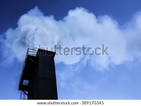 Dramatic industry chimney silhouette exausting co2 in the atmosphere.