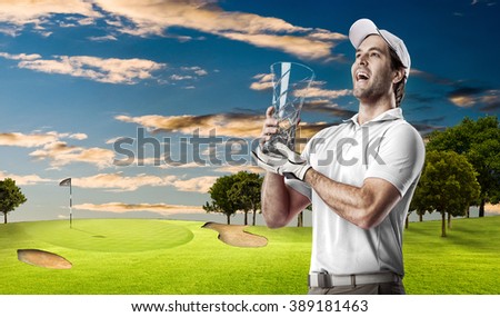 Golf Player in a white shirt celebrating with a glass trophy in his hands, on a golf course.