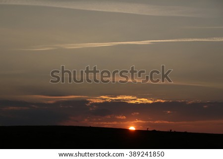 Wonderful sundown end of day at field with beautiful layer clouds in sky red sun and sunbeams in twilight at summer season outdoor, horizontal picture