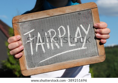 FAIRPLAY written with chalk on writing slate shown by young female Royalty-Free Stock Photo #389251696