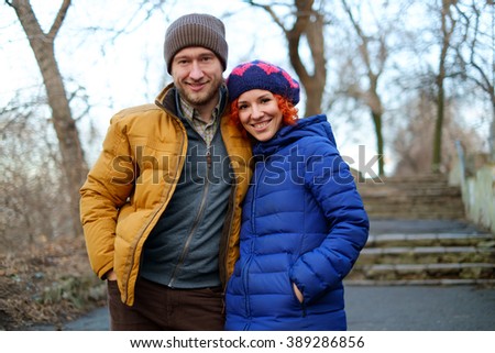 Beautiful woman and man hugging on the street in sunny fall. Autumn love story. Young fashion couple in love smiling and having fun in park. Bright picture of family couple in a wool winter clothing.