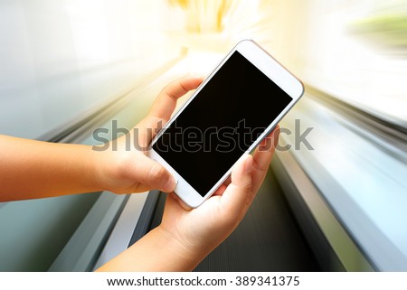 hand of child holding mobile phone with blur perspective escalator background