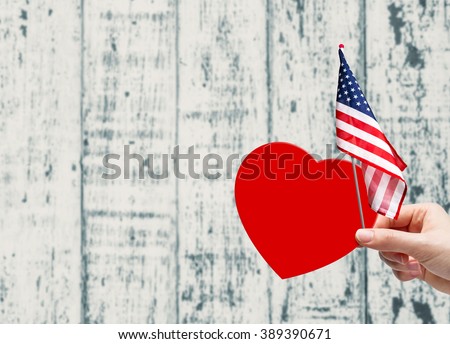 Hand holding red paper heart and USA flag