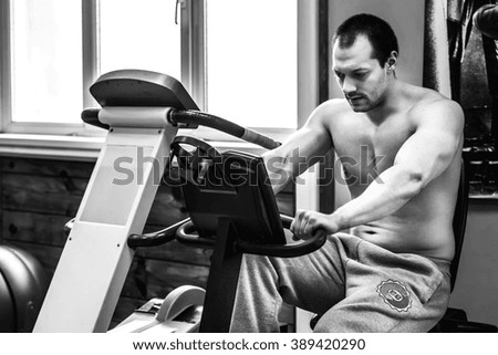 Man training on exercise bike in fitness center, black and white photography