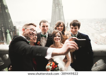Bridesmaids, groomsmen and wedding couple making selfie with panoramic view of the city