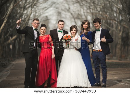 Bridesmaids and groomsmen with wedding couple posing in park 