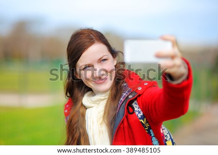 Young woman taking a outdoors self portrait (selfie) with smart phone 