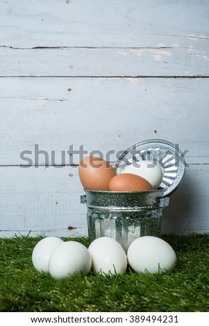 Fresh Easter eggs In Garbage Can on grass with a wood background