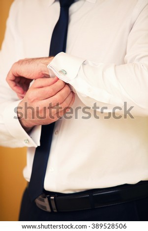 groom dresses cuff links on cuffs
