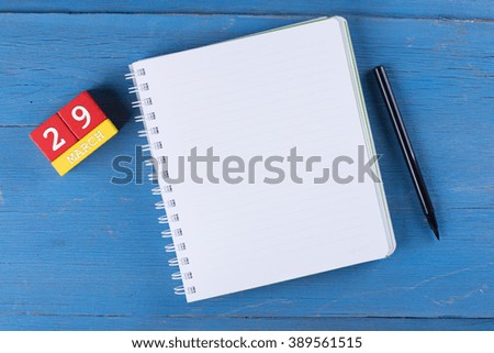 March 29, Cube calendar and notebook on wooden surface with copy space