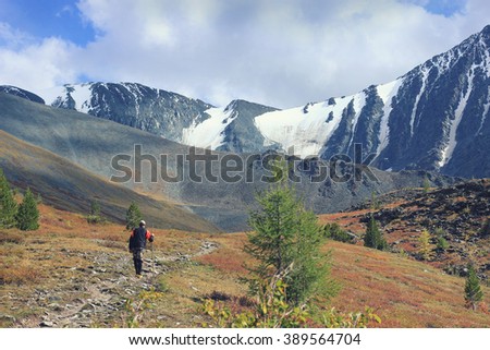 Backpacker go into the mountains. Happy travel concept. Mountain trekking. Man in harmony with nature. Autumn mountain landscape. Russia. Karaturek pass. 