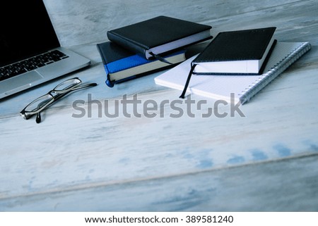 Stylish modern workspace work desktop with diary notebooks glasses on the wooden vintage table background wide angle 
