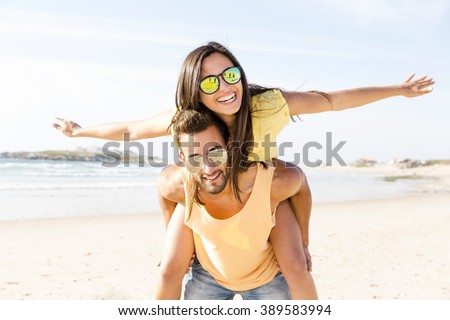 Young couple having fun at the beach Royalty-Free Stock Photo #389583994