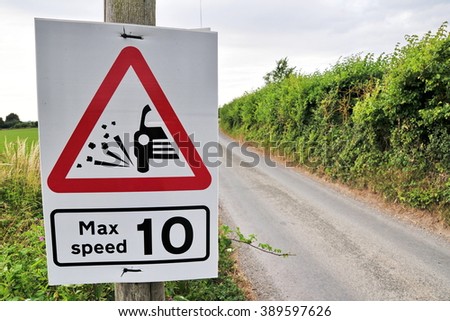View of a Speed Limit Road Sign Warning of Loose Gravel on a Country Road