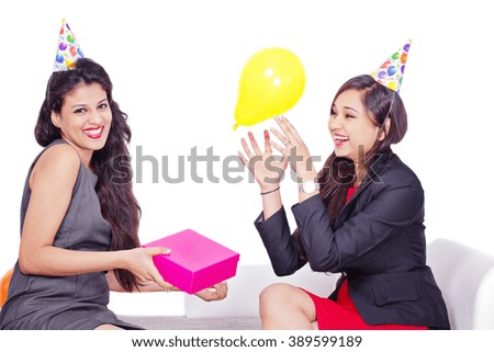 Two woman celebrate birthday, one holds gift box, another surprised