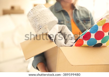 Young woman holding open cardboard box with things for moving into new house Royalty-Free Stock Photo #389599480