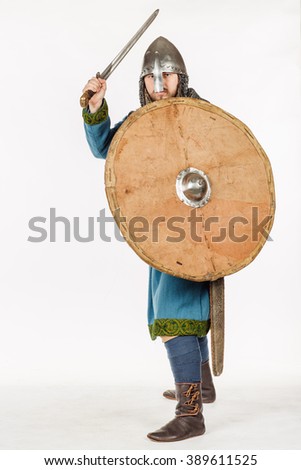 medieval slavic soldier standing and ready for a fight with sword, helmet, hauberks. image on white studio background. historical concept.