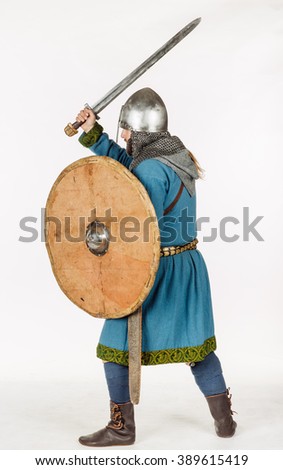 medieval slavic soldier standing and ready for a fight with sword, helmet, hauberks. image on white studio background. historical concept.