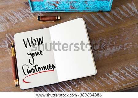 Retro effect and toned image of a woman hand writing a note with a fountain pen on a notebook. Handwritten text WOW Your Customers as business concept image Royalty-Free Stock Photo #389634886
