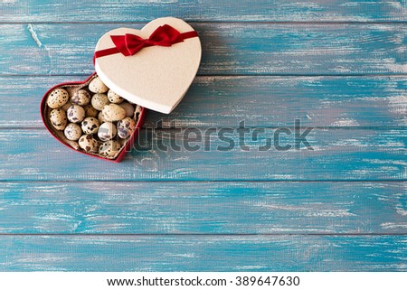 quail eggs lying in a heart shaped gift box on the texture blue table with free space for text