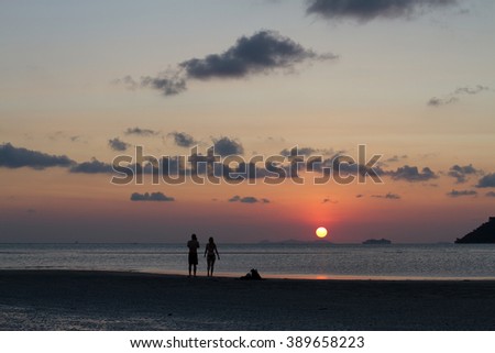 Silhouette shot of unidentified couple taking photo of the sun going down into the ocean with beautiful orange color sun and sky on koh samui island, the southern part of Thailand during summer time