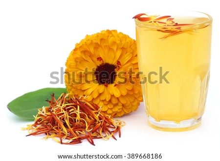 Herbal calendula flower with extract in a glass over white background