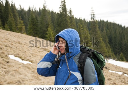 Hiker talking on the smartphone in the winter mountains. Mobile communications in the mountains