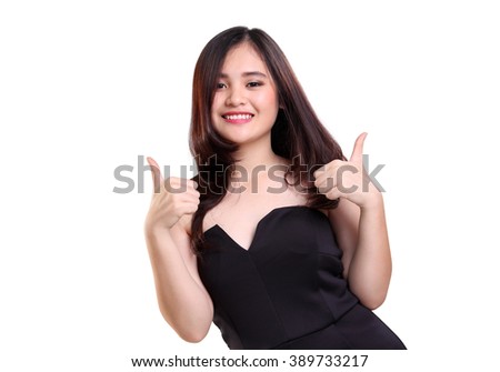 Beautiful smiling young Asian woman in stylish black top dress giving two thumbs up, isolated on white background