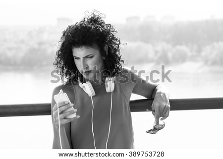 Portrait of beautiful woman with curly black hair with headphones. Black and white.