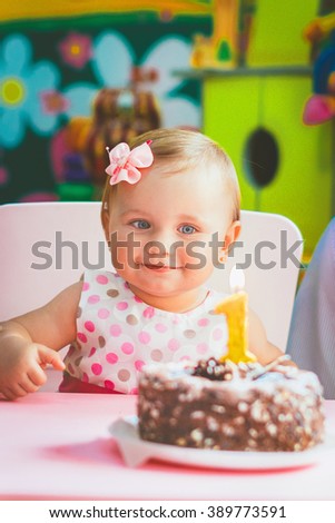 kids birthday, the girl at the table with cake and candles on the cake looks