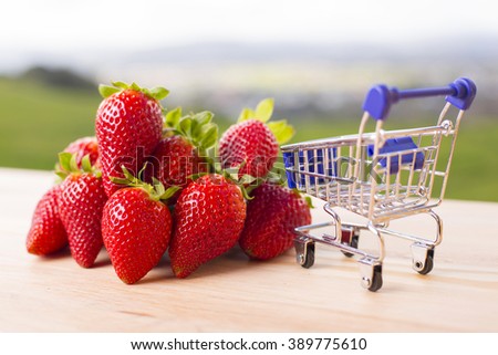 strawberries and a shopping cart on garden's table, outdoor picture