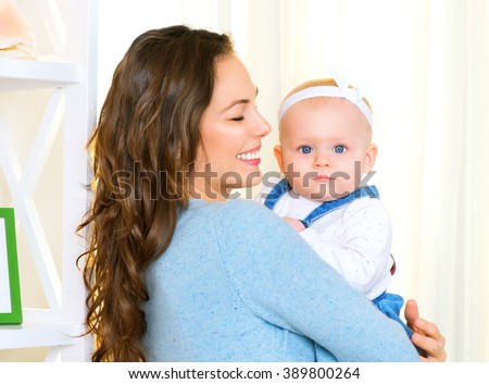 Mother and Baby smiling together. Love. Happy cheerful family Mom and Baby girl kissing and hugging at home. Beautiful healthy mother and little daughter. Maternity concept. Parenthood. Motherhood 