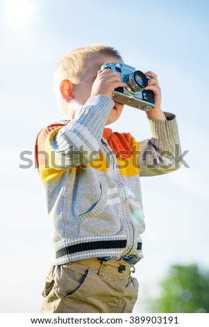 Little boy with an old camera shooting outdoor.