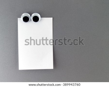 eyes man fridge magnet with blank note paper on gray metal refrigerator door, cute eyeball magnetic and notepaper for writing messages to communicate and reminder, close-up with copy space for text