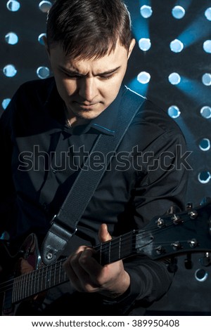 Portrait of young man playing on electric guitar on stage