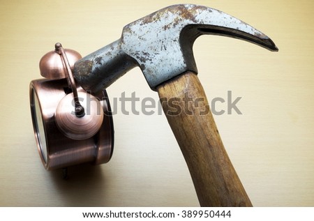 Old rusty hammer with alarm clock on wooden background.