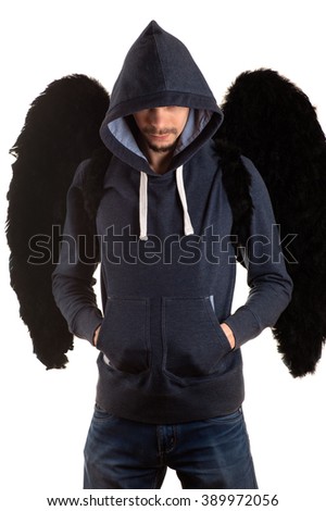 young man in gray jacket and blue jeans with hood thrown over his head standing with his hands in his pockets and on the back with black wings