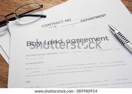 pen and land contract form on wood background.Business buy and sell home concept.