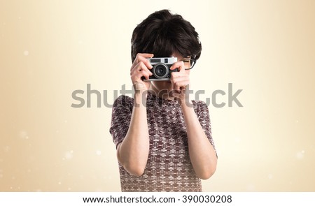 Girl with pop look photographing over ocher background