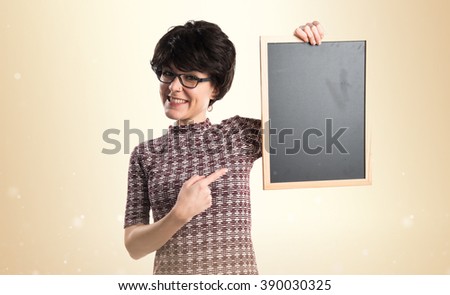Brunette girl holding an empty placard over ocher background