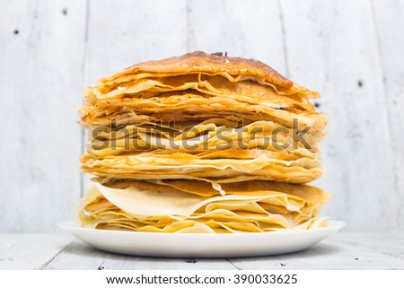 A huge stack of thin russian pancakes on a white wooden background