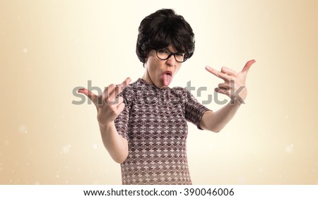 Girl with pop look making horn gesture over ocher background
