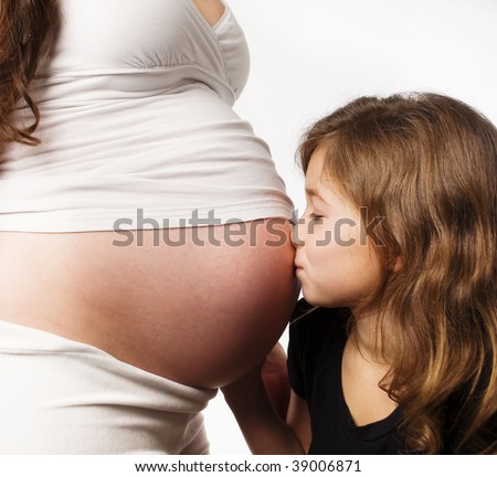 Little girl kissing her moms pregnant tummy belly