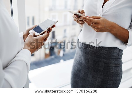 Closely up of women lawyers are using their mobile phones during break between court session. Two young female managers are searching needed information for work in internet via cell telephones