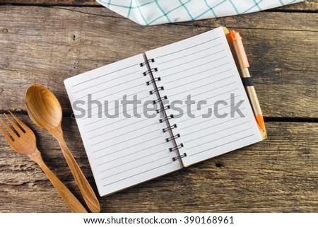 blank recipe book with kitchen utensils on wooden background 