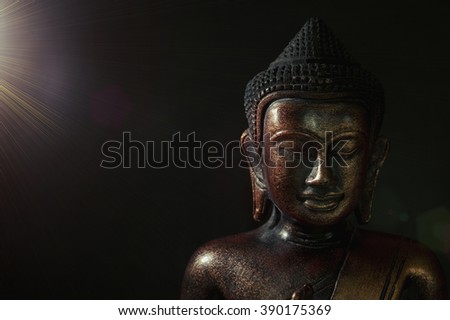 Wooden bronze buddha on black blurred background close up