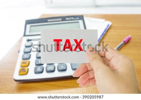 hand hold card with word tax on blur background photo of calculator, receipt and pen on wood table