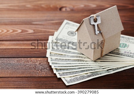 Model of cardboard house with key and dollar money. Building, insurance, housewarming, loan, real estate, cost of housing or buying a new home concept.