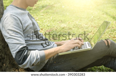 young man with phone and llaptop outdoors